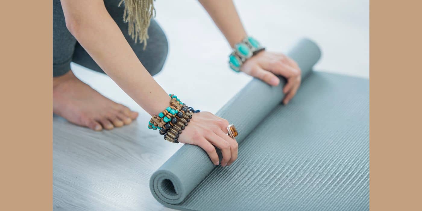Holistic living path top 6 supreme yoga mats from amazon and they're importance for a well-rounded practice image of a woman rolling a light blue yoga mat..