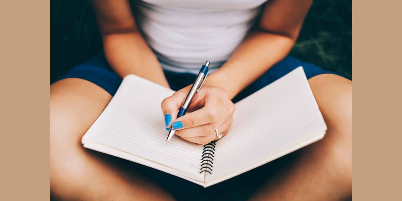 Woman sitting cross-legged journaling.