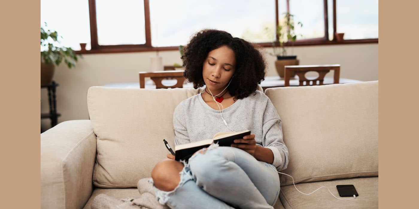 Woman journaling on the couch.
